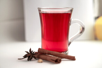 a glass cup of a red warming drink (tea, mulled wine, punch). ingredients for winter hot drinks.