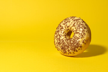 Yellow donut with chocolate crumbs on yellow background. Creative food background