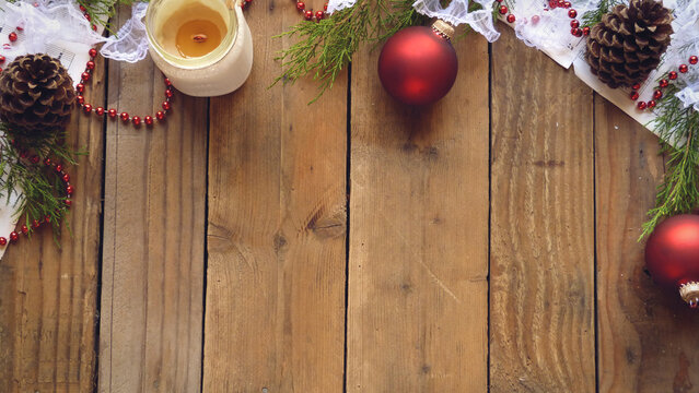 Christmas Flatlay of Pine Cones, Red Ornaments, Beads, Sheet Music, Candle, and Evergreen Boughs on a Wooden Background | Rustic Christmas Decorations