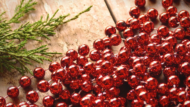 Close Up of Red Beads with Evergreen on a Wooden Background | Red Christmas Beads | Rustic Christmas