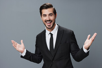 Business man has his hands up and is smiling with his teeth open in a business suit on a gray background portrait