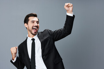 Business man happy smile with teeth open mouth raised hands up fists bump winner on gray background in business suit. 