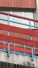 Barandilla de tablones de madera rojo y barrotes de metal azul
