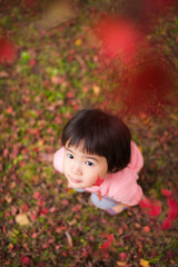 紅葉が綺麗な公園で自然を楽しむ3歳の女の子