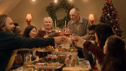 Happy multi cultural family celebrating Christmas or New Year, raising glasses with wine. Served...