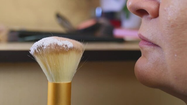I blow off excess powder from a cosmetic brush