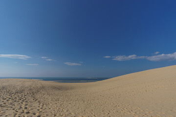 Fototapeta na wymiar Sand dune, atlantic sea and blue cloudy sky, Dune du Pilat, Arcachon, Nouvelle-Aquitaine, France