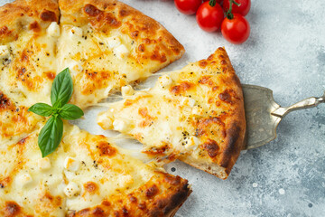 Italian pizza four cheeses with stretching cheese and basil on a light concrete background