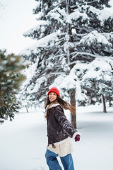 Fototapeta na wymiar Young woman laughs and throws snow in a winter snowy park. Holidays, rest, travel concept.