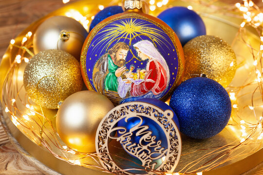 a large decoration for the Christmas tree with the image of the birth of Jesus Christ in Bethlehem. Against the background of gold and blue balls and bright led flashlights