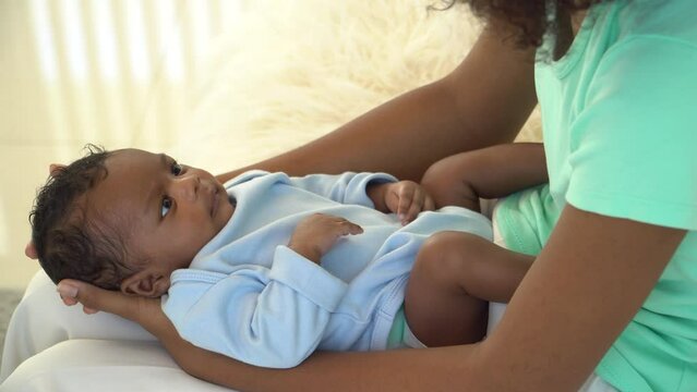 Portrait of African newborn baby one-month-old cheerful curious sleep in warm embrace of motherhood. Mother playful holding Adorable little infant son develop, with, Mum and child tender moments.