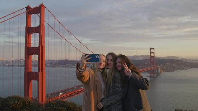 Pretty, caucasian girls in their 20s enjoying cinematic sunset over Bay Area in SF city. Female friendship, travel together to iconic tourist destinations concept. High quality 4k footage