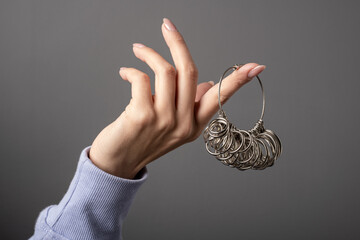 Finger Sizing Gauge Rings Measurement .Woman hand holding Ring Sizer Measuring Wedding Jewelry Size Tool Set. Metal