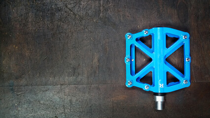 blue aluminium Flat Pedal with interchangeable spikes on a dark wooden background top view