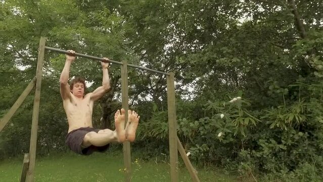 Athletic young man does L-Sit pullups on outdoor home gym