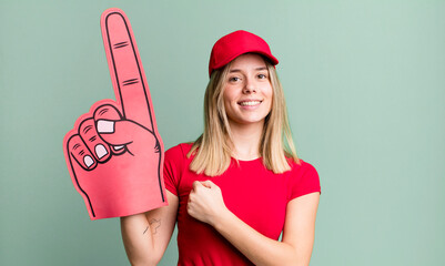 young pretty woman feeling happy and facing a challenge or celebrating. number one fan concept