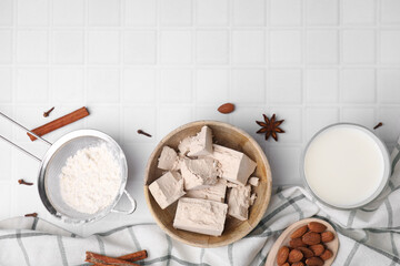 Bowl with compressed yeast, flour and other ingredients on white tiled table, flat lay. Space for text