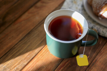 Tea bag in cup on wooden table, closeup. Space for text