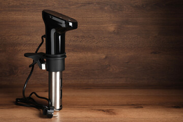 Thermal immersion circulator on wooden table, space for text. Sous vide cooker