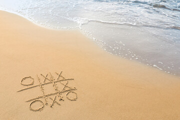 Tic tac toe game drawn on sand near sea, space for text