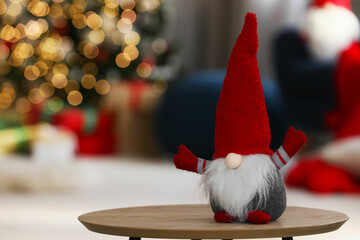 Cute Christmas gnome on wooden table in decorated room, space for text