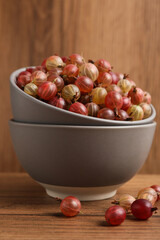 Bowls full of ripe gooseberries on wooden table