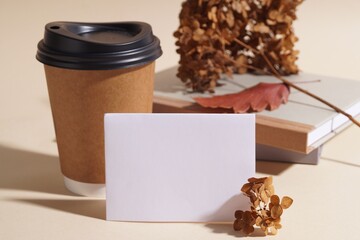 Dried hortensia flowers, sheet of paper and cardboard cup on beige table. Space for text