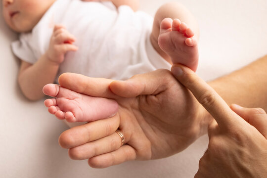 Children's foot in the hands of mother, father, parents. Feet of a tiny newborn close up. Little baby legs. Mom and her child. Happy family concept. Beautiful concept image of motherhood stock photo. 