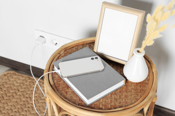 Modern smartphone charging on round rattan table indoors