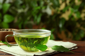 Fresh green tea in glass cup and leaves on table