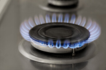 Gas burner with burning flame on cooktop, closeup