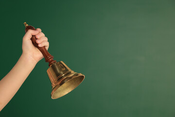 Pupil with school bell near chalkboard, closeup. Space for text