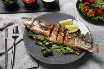 Delicious sea bass fish and ingredients served on light grey table