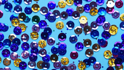Many different sequins on light blue background, flat lay
