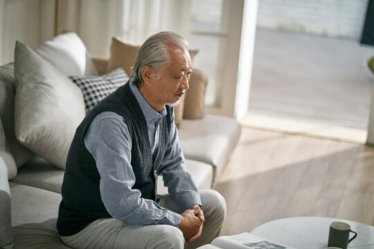 Sad Asian Old Man Sitting Alone On Couch At Home