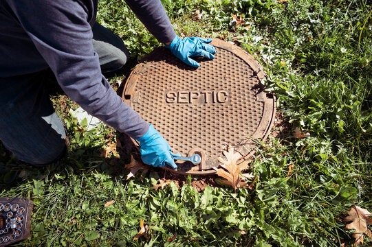 A working plumber opening septic system tank. Copy space for text.