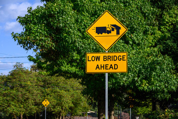 Yellow road sign, Low Bridge Ahead with a truck and bridge symbol, caution to tall vehicles

