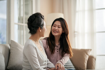 asian adult daughter and senior mother enjoying conversation at home