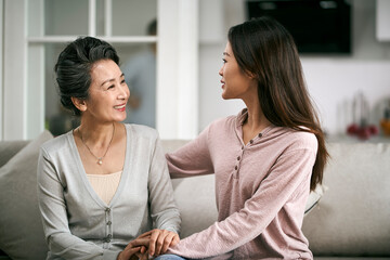 asian adult daughter and senior mother enjoying conversation at home