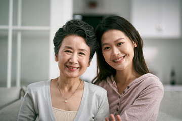 portrait of asian senior mother and adult daughter looking at camera smiling - Powered by Adobe