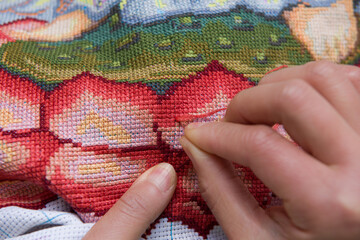 Woman hands working cross-stitch. A close up of embroidery.