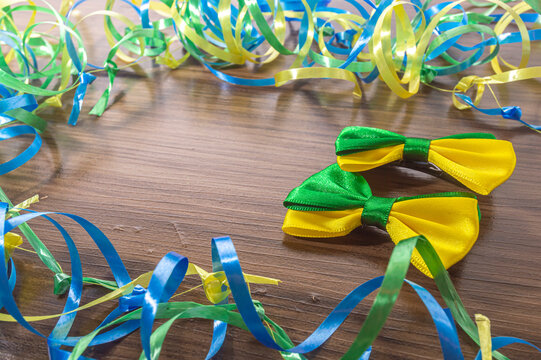 Bow tie with brazil colors on a wooden table with green, yellow and blue ribbons