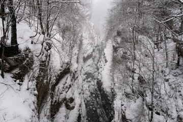 Urukh river canyon from Devil's Bridge at winter snowfall. Mountain Digoria, North Ossetia, Russia.