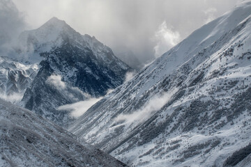 Uavsikhoh Mount (3856 m) and Aygamuga river gorge at stormy winter day. View from Kamunta village. Mountain Digoria, North Ossetia, Russia.