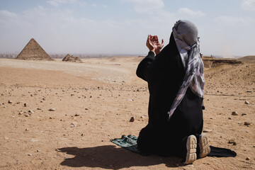 A Muslim with robe clothes praying on the desert