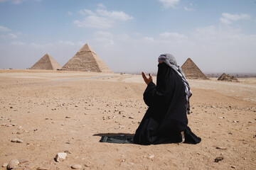 A Muslim with robe clothes praying on the desert
