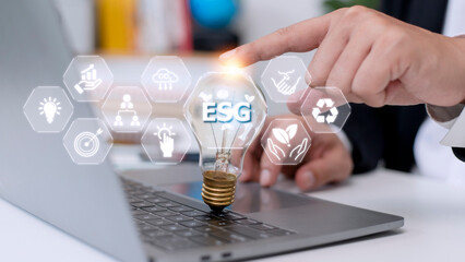 Businessman hand holding light bulb with esg icon on virtual screen, ESG Environmental, social and corporate governance concept