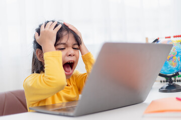 Asian child is serious about studying homework during online lesson at home, social distancing during quarantine, self-isolation, online education concept, homeschooling, 