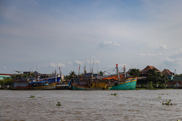 Fototapeta na wymiar Ho Chi Minh City, Vietnam- November 9, 2022: Fishing boats on the Mekong river on the river bank of the Mekong Delta. Fishing village in the evening during sunset. Panoramic view over the Mekong river