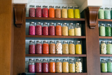 Candy toppings in jars on several shelves inside a confectionery shop or bakery